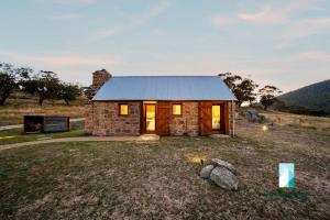 ein Steinhaus mit einem Metalldach auf einem Feld in der Unterkunft The Stone Cottage at Wollondibby - Heritage Listed l Renovated l Fire Place in Crackenback