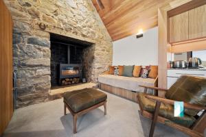 ein Wohnzimmer mit einem Steinkamin und einem Sofa in der Unterkunft The Stone Cottage at Wollondibby - Heritage Listed l Renovated l Fire Place in Crackenback
