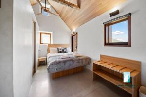 ein Schlafzimmer mit einem Bett und einer Bank darin in der Unterkunft The Stone Cottage at Wollondibby - Heritage Listed l Renovated l Fire Place in Crackenback