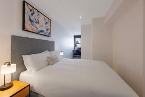 a bedroom with a large white bed and a table at Flinders Luxury Penthouse in Melbourne