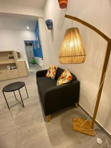 a living room with a black couch and a lamp at NINA, a centrally located summery studio apartment in Il-Gżira +8 photos