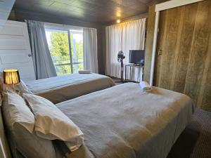 a hotel room with two beds and a window at Aorangi Peak Cottage in Rotorua