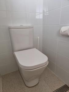 un aseo blanco en un baño de azulejos blancos en Elfin Hill Vineyard Accommodation, en Pokolbin