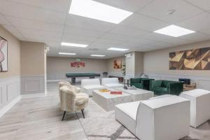 uma sala de espera com mobiliário branco e uma mesa de bilhar em Flamboyant 1BR Near EWR w/ Gym em Newark