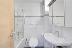 a white bathroom with a toilet and a sink at Good Value Apartments by Mountain Exposure in Zermatt