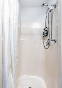 a white bathroom with a shower and a toilet at CozySuites CWE Double Queen Suite in Saint Louis