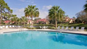 a large swimming pool with chairs and palm trees at Beachwalk Villa 5117 in Destin