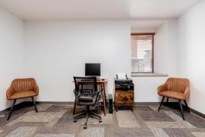 an office with two chairs and a desk and a television at CozySuites CWE Double Queen Suite in Saint Louis