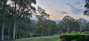 a park with trees in a field with the sunset at Elfin Hill Vineyard Accommodation in Pokolbin