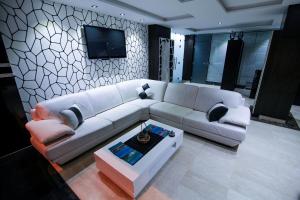 Hotel Jedda douhi el ouassini في وجدة: غرفة معيشة مع أريكة بيضاء وتلفزيون