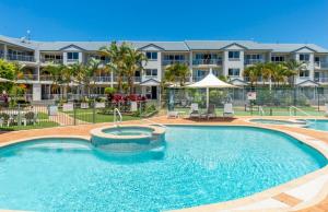 a swimming pool in front of a large apartment building at Pelican Cove Apartments in Gold Coast
