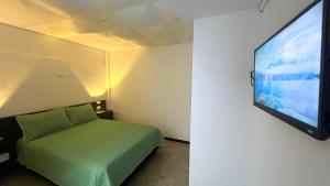 a room with a green bed and a flat screen tv at Apartaestudio Aguamarina in Líbano