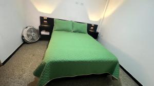 a green bed in a small room with a fan at Apartaestudio Aguamarina in Líbano