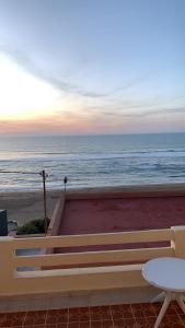 um banco e uma mesa e o oceano ao pôr-do-sol em EL MAR BEACH em Moulay Bousselham