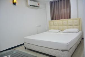 Cama blanca en habitación con ventana en Saasha City Hotel, en Colombo