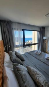 - une chambre avec un grand lit et une grande fenêtre dans l'établissement Nova Patagonia Apart Bariloche, à San Carlos de Bariloche