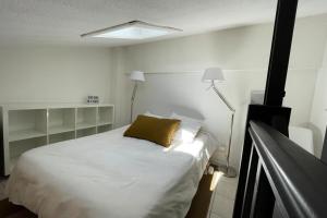 a bedroom with a white bed with a yellow pillow at Charming Mazet ideal for families swimming pool tennis in Maussane-les-Alpilles