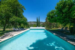 a swimming pool in a yard with chairs and trees at Villa Les Saffres in Malaucene in Malaucène