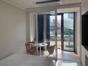 Un dormitorio con una cama y una mesa y un balcón. en Urbanstay Myeongdong, en Seúl 37 fotos más