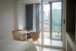 1 dormitorio con mesa, sillas y balcón en Urbanstay Myeongdong, en Seúl