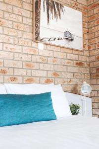 a bedroom with a white bed and a brick wall at Kennedy Drive Airport Motel in Tweed Heads