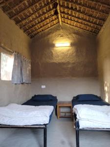 BhagauraにあるIshq Sanctum- A Conscious Guest Houseのベッド2台とテーブルが備わる客室です。