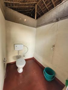 a bathroom with a toilet and a bucket at Ishq Sanctum- A Conscious Guest House in Bhagaura