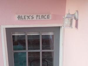 Alex's Place - Tim Pappies في بورت أنطونيو: علامة فوق باب مع نافذة زجاجية