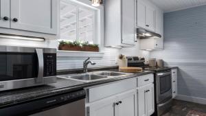 a white kitchen with a sink and a microwave at Enchanted Haus walk to Main hot tub on balcony in Fredericksburg