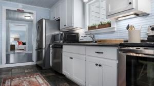 a kitchen with white cabinets and a stainless steel refrigerator at Enchanted Haus walk to Main hot tub on balcony in Fredericksburg