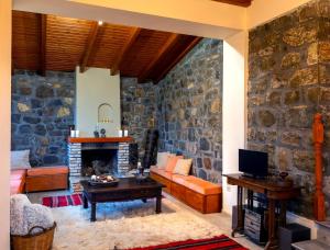 sala de estar con pared de piedra en Marianda's House - Mountain Views & Rustic Charm, en Tíkhion