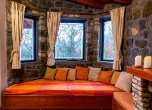 um sofá num quarto com duas janelas em Marianda's House - Mountain Views & Rustic Charm em Tíkhion
