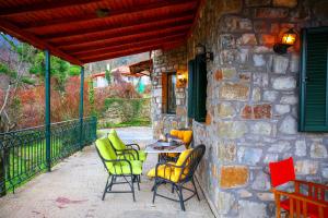 un patio con sillas y una mesa en una pared de piedra. en Marianda's House - Mountain Views & Rustic Charm, en Tíkhion