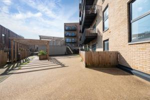 a courtyard with a fence and a building at Stylish 1BR Flat with Balcony Near Tube and Shops in Woolwich