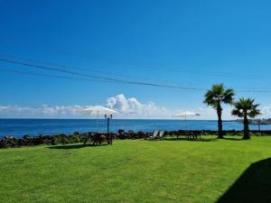 um parque com mesas e guarda-sóis e o oceano em The Villas Ocean for Family em Seogwipo