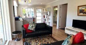 a living room with a black leather couch and a television at Waikanae Beach Suite Retreat in Waikanae