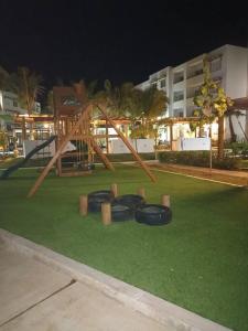 un parque infantil con marco de madera en la hierba en Departamento Planta Baja, A 1 Minuto de la playa., en Mazatlán