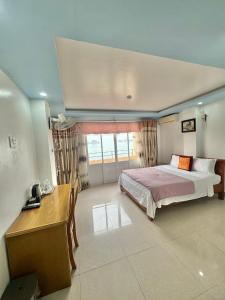 a bedroom with a bed and a desk and a window at New Way Hotel in Cat Ba