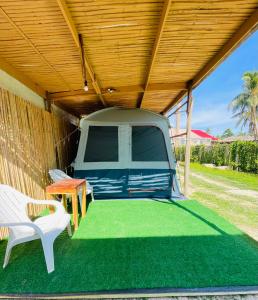 a van parked under a wooden roof with a table and chairs at Russell Place Tent in Port Barton