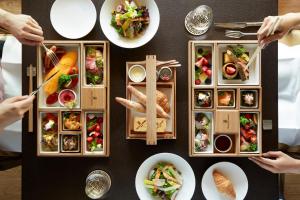 une table remplie de assiettes de nourriture avec des gens mangeant dans l'établissement The Ritz-Carlton, Nikko, à Nikkō