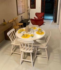 una mesa blanca y sillas en la sala de estar. en Casa Aconchego Guaramiranga, en Guaramiranga