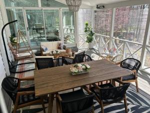 Habitación con balcón con mesa de madera y sillas. en Tara Retreat: Family-Friendly Oasis with Pool, Tennis & Serene Ambiance in Potomac, en Potomac