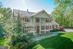 a large white house with red windows and a yard at Tara Retreat: Family-Friendly Oasis with Pool, Tennis & Serene Ambiance in Potomac in Potomac