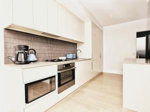 a kitchen with white cabinets and a stove at Iconic on Vue with Free Parking Pool Gym CBD in Adelaide