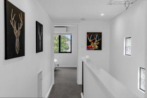 - un couloir blanc orné d'œuvres d'art sur les murs dans l'établissement 2BR Townhouse CBD Chinatown Free WiFi FreeParking, à Adélaïde 32 autres photos