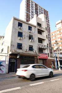 a white car driving down a street in front of a building at Hotel city Clélia in Sao Paulo