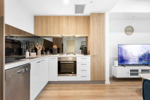a kitchen with white cabinets and a flat screen tv at The elegant 1BR CBD Apt - City view - Parking in Adelaide