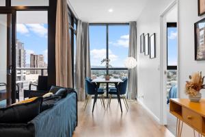 a living room with a couch and a table with chairs at The elegant 1BR CBD Apt - City view - Parking in Adelaide +24 photos