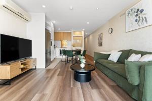 a living room with a green couch and a flat screen tv at 2BR CBD Apt Swimming Pool Sauna SPA CBD in Adelaide