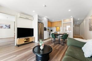 Una sala de estar con un sofá, un televisor y una mesa. en 2BR CBD Apt Swimming Pool Sauna SPA CBD, en Adelaida